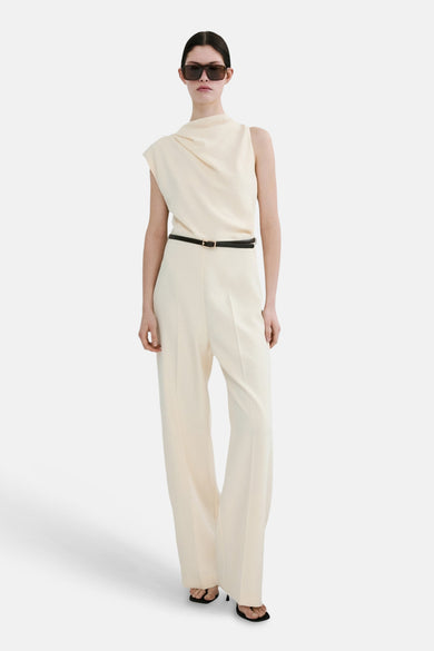 Combinaison écru de MANGO, cintrée avec une fine ceinture noire à boucle dorée et jambes longues.