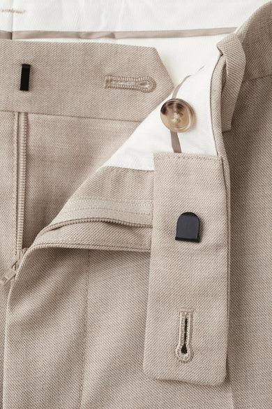 Pantalon de costume beige de MANGO, avec une fermeture à glissière partiellement ouverte et une fermeture à bouton.
