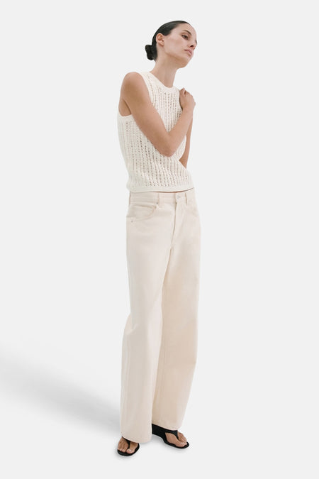 Haut sans manches écru de MANGO, avec une texture en maille ajourée, associée à un jean large de couleur crème et des sandales.