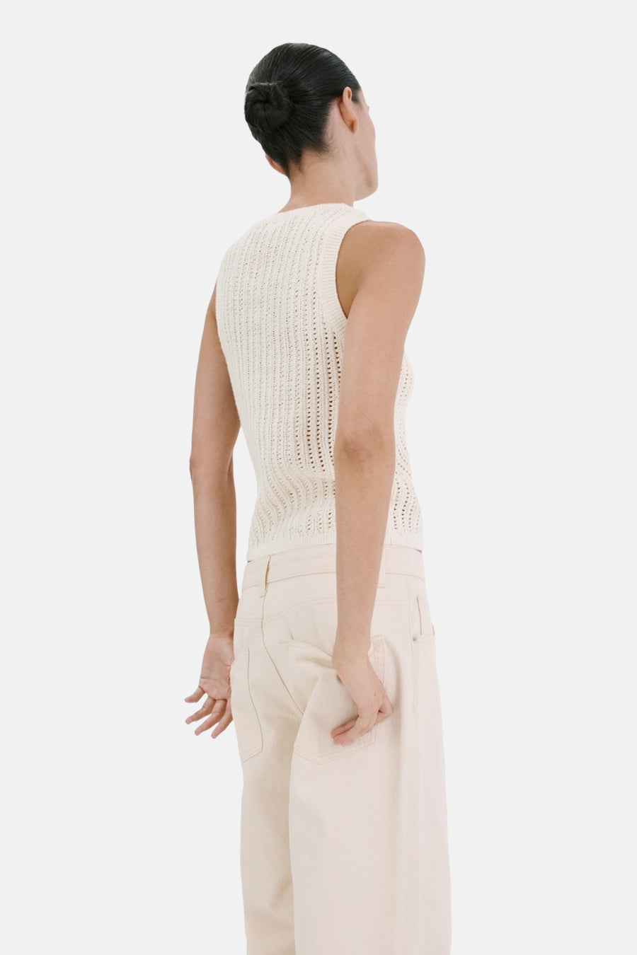 Haut écru sans manches de MANGO, avec une texture crochetée et portée avec un pantalon de couleur crème.