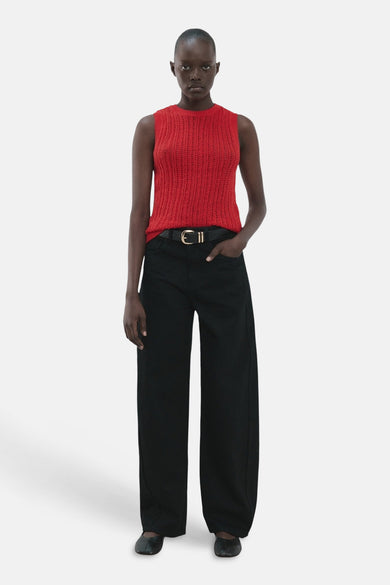 Haut rouge sans manches de MANGO, avec une texture en maille ajourée et combinée avec un pantalon noir et une ceinture.
