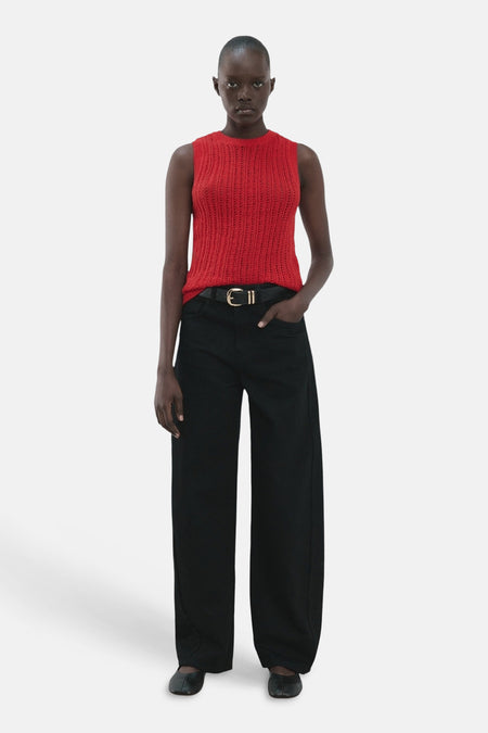 Haut rouge sans manches de MANGO, avec une texture en maille ajourée et combinée avec un pantalon noir et une ceinture.