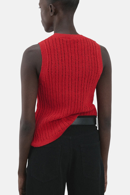 Haut sans manches rouge de MANGO, avec une texture ajourée, combinée à un pantalon noir et une ceinture.