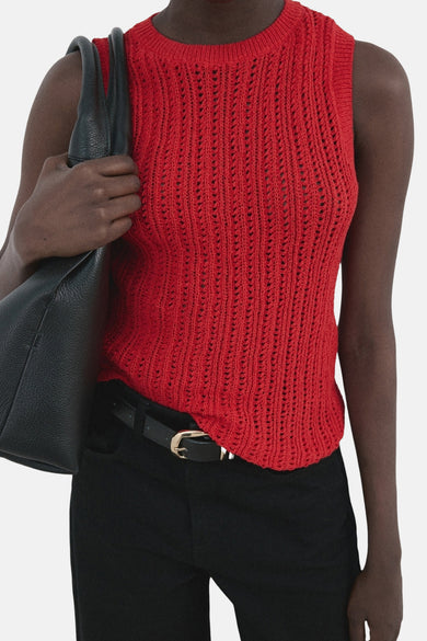 Haut rouge sans manches de MANGO, avec un motif ajouré et combiné avec un pantalon et un sac noirs.