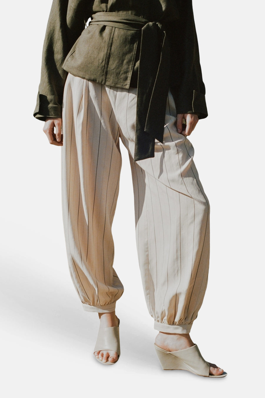 Pantalon écru de MANGO avec fines rayures verticales, coupe ample et chevilles élastiques.