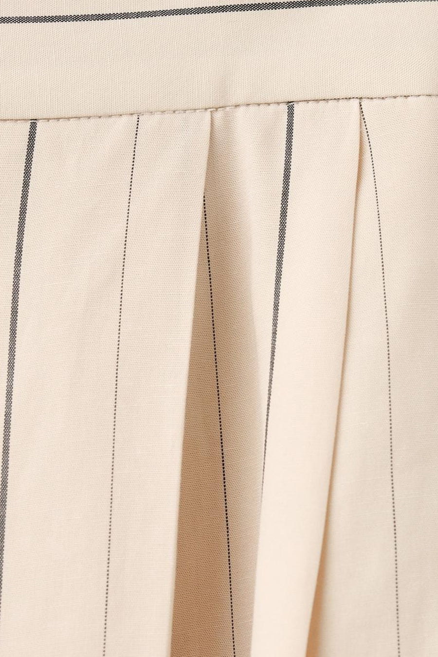 Pantalon écru de MANGO avec rayures craie et plis, gros plan.