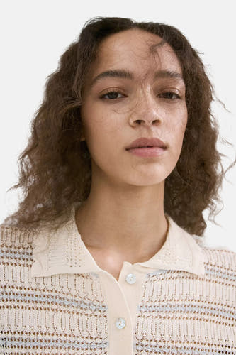 Polo en tricot écru de MANGO avec motif ajouré et fines rayures bleu clair.