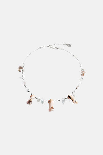 Collier court multicolore de MANGO avec coquillages et perles, porté avec un haut noir au crochet et un short rayé.