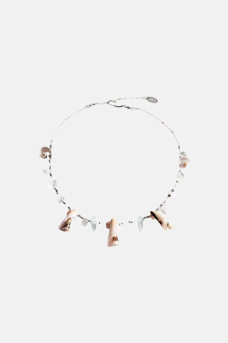Collier court multicolore de MANGO avec coquillages et perles, porté avec un haut noir au crochet et un short rayé.