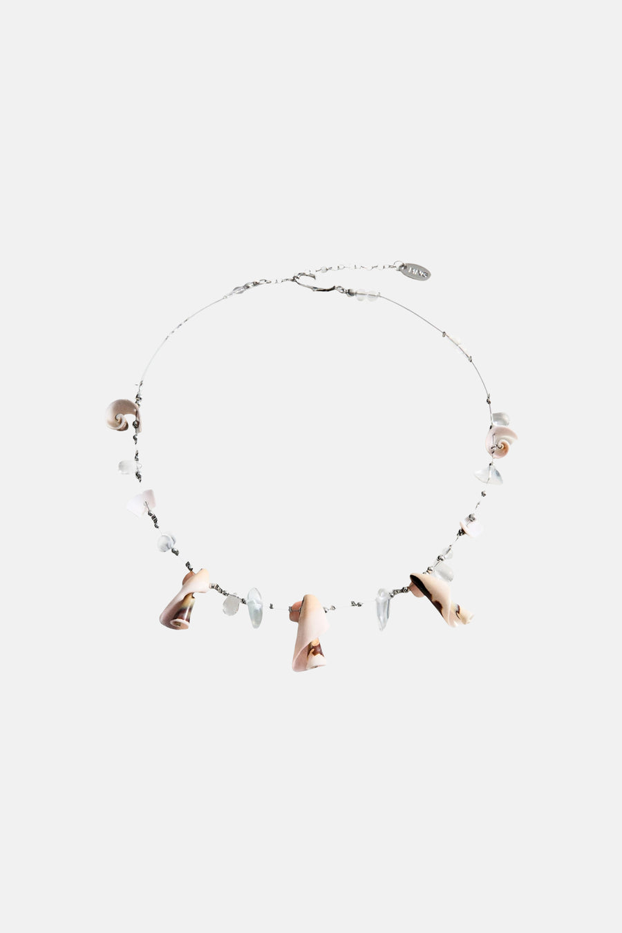 Collier court multicolore de MANGO avec coquillages et perles, porté avec un haut noir au crochet et un short rayé.