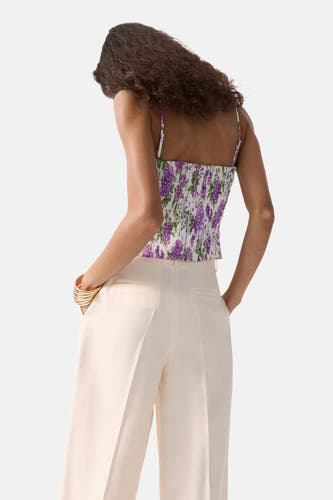 Multicolor mouwloze blouse van MANGO met paarse bloemenprint, gesmokte achterkant en gedragen met lichte broek en gouden armbanden.