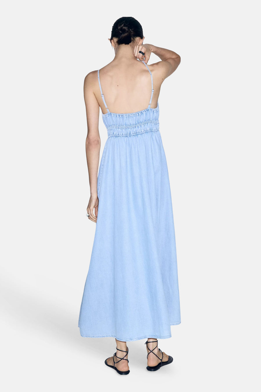 Lichtblauw denimkleedje zonder mouwen van MANGO, met smalle bandjes en geruchte taille, achterkant weergegeven, model draagt zwarte sandalen