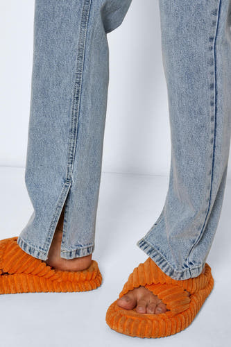 Jean droit bleu clair de NOISY MAY, avec des découpes aux chevilles, associé à des chaussons orange.