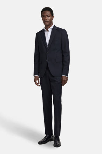 Pantalon de costume bleu MANGO, porté avec un chemisier blanc et des chaussures noires.