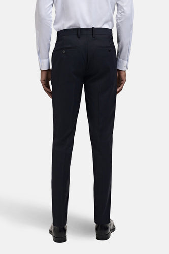 Achterkant van een man in een wit overhemd, donkerblauwe pantalon en zwarte leren schoenen.