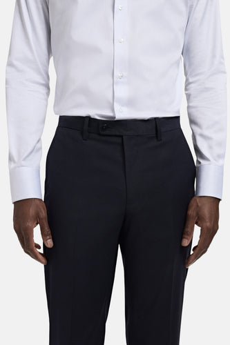 Close-up van een persoon in een wit overhemd en donkerblauwe pantalon.