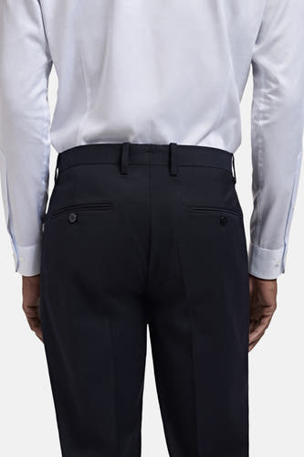 Pantalon de costume bleu MANGO, avec des poches arrière et des passants, porté avec un chemisier rayé.