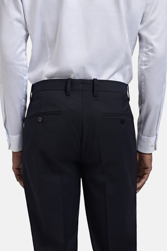 Achterkant van een persoon in een blauw gestreept overhemd en donkerblauwe pantalon.