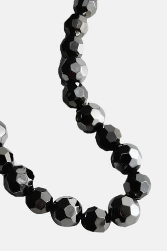 Courte chaîne d'argent de MANGO, avec des perles facettées sur un fond blanc.