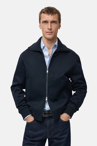 Gilet bleu de MANGO, vu d' dosrière, combiné avec un jeans bleu marine.