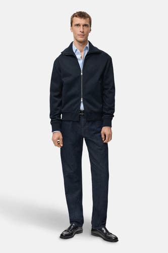 Gilet bleu de MANGO, avec des fermetures éclair argent et porté avec un un unau clair, un jeanss et des chaussures noires.
