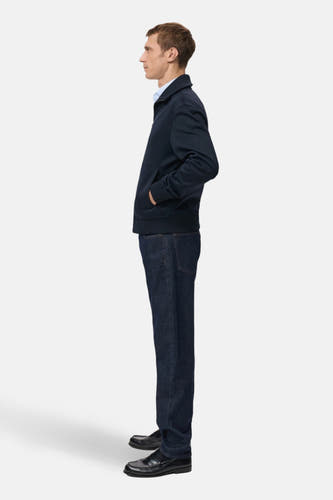 Gilet bleu de MANGO, avec des poches, porté avec un chemisier bleu, des jeans foncés et des chaussures noires, en vue latérale.