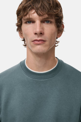 Pull-over bleu avec col rond de MANGO, porté sur une chemise blanche, gros plan.