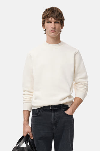 Pull-over blanc de MANGO, vu de l'arrière, avec des manches longues et un jeans foncé.