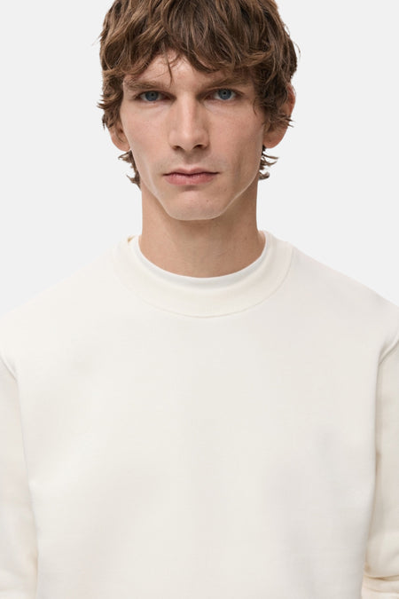 Man met blauwe ogen in een crèmekleurige sweater.
