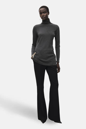 Sweat-shirt gris à col rond de MANGO, associé à un pantalon noir avec des jambes larges et des accessoires élégants.