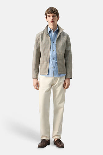 Veste courte multicolore de MANGO, portée avec une chemise bleu clair et un pantalon beige.