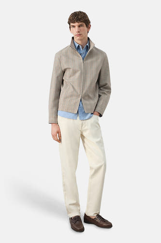 Veste courte multicolore de MANGO, à motif à carreaux et fermeture éclair, associée à une chemise bleue et un pantalon beige.