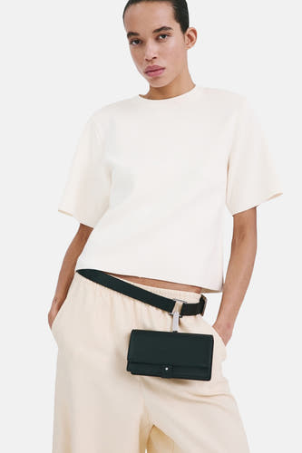 Pull écru à col rond de MANGO, vu de dos, combiné avec un pantalon de couleur crème.