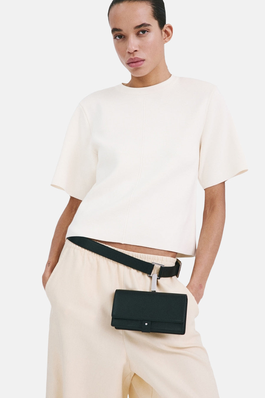 Pull écru à col rond de MANGO, vu de dos, combiné avec un pantalon de couleur crème.
