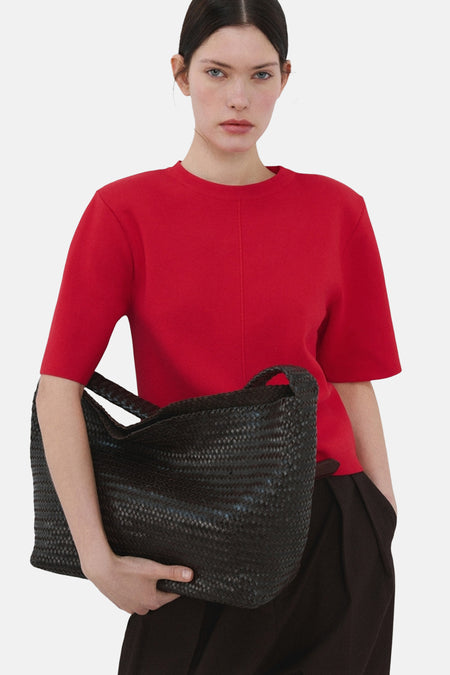 Pull rouge à col rond de MANGO, vu de dos, combiné avec un pantalon foncé et des talons.