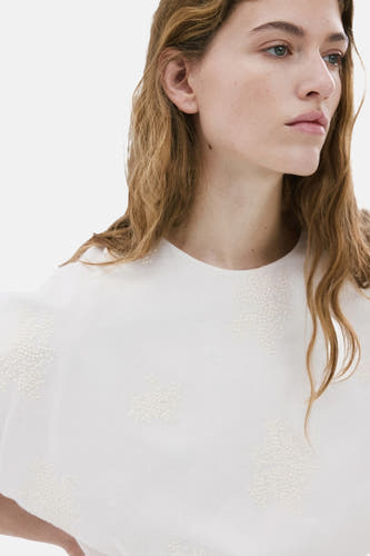 Blouse écru à manches courtes de MANGO, ornée d'un délicat motif à pois sur le tissu.