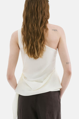 Witte mouwloze blouse van MANGO met één schouder en gedrapeerde stof, aan de achterkant gedragen door een model.