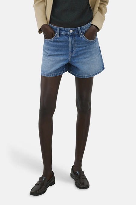 Bermuda en jean de couleur bleu moyen de MANGO, avec ceinture marron foncé et poches arrière, côté dos.