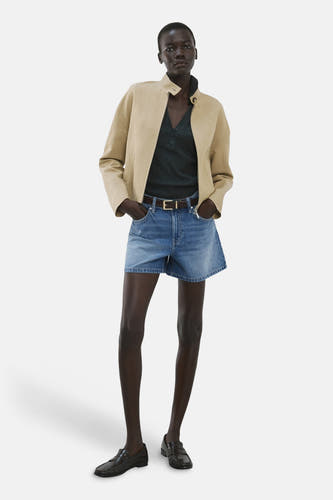 Bermuda short en jean bleu moyen de MANGO, combiné avec une veste beige et des mocassins noirs.