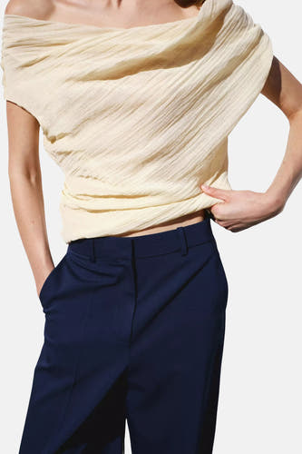 Pantalon de costume bleu de MANGO, taille haute, porté avec un haut texturé de couleur crème.