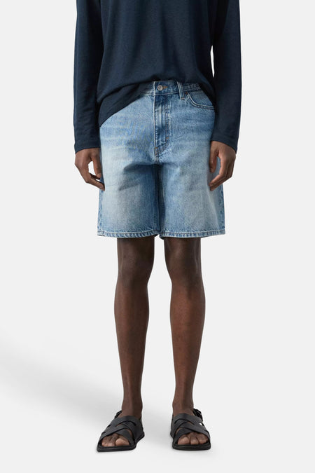 Bermuda en denim bleu moyen de MANGO, gros plan sur la poche avant avec rivets couleur bronze et coutures.