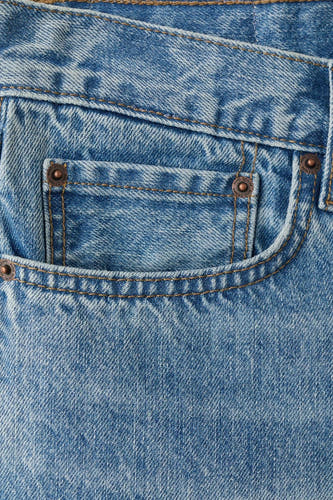 Mid-blauwe denim bermuda van MANGO, close-up van de voorzak met bronskleurige klinknagels en stiksels.