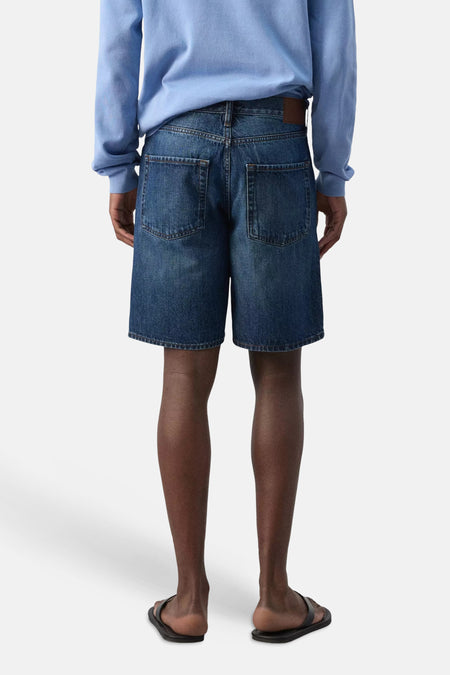 Donkerblauwe denim bermuda van MANGO, achterkant, met opgestikte zakken en bruine leren patch.