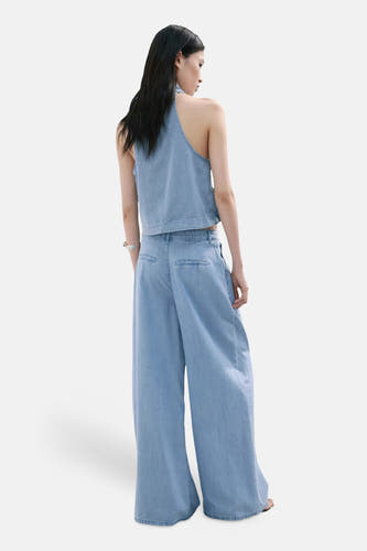 Lichtblauwe denimbroek met wijde pijpen van MANGO, achterzijde weergegeven, met bijpassend topje en zilveren armband