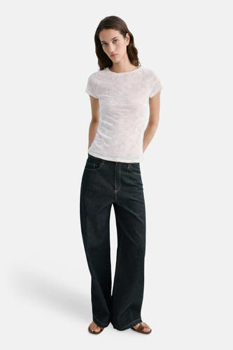 Beige korte mouwen t-shirt van MANGO met fijne ribstructuur, gedragen met donkere jeans en sandalen, front view.