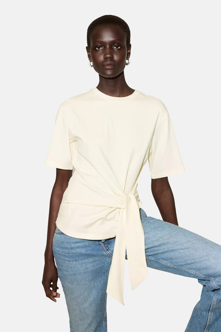 Gele korte mouwen t-shirt van MANGO met knoopdetail aan de zijkant, gedragen met blauwe jeans, front view