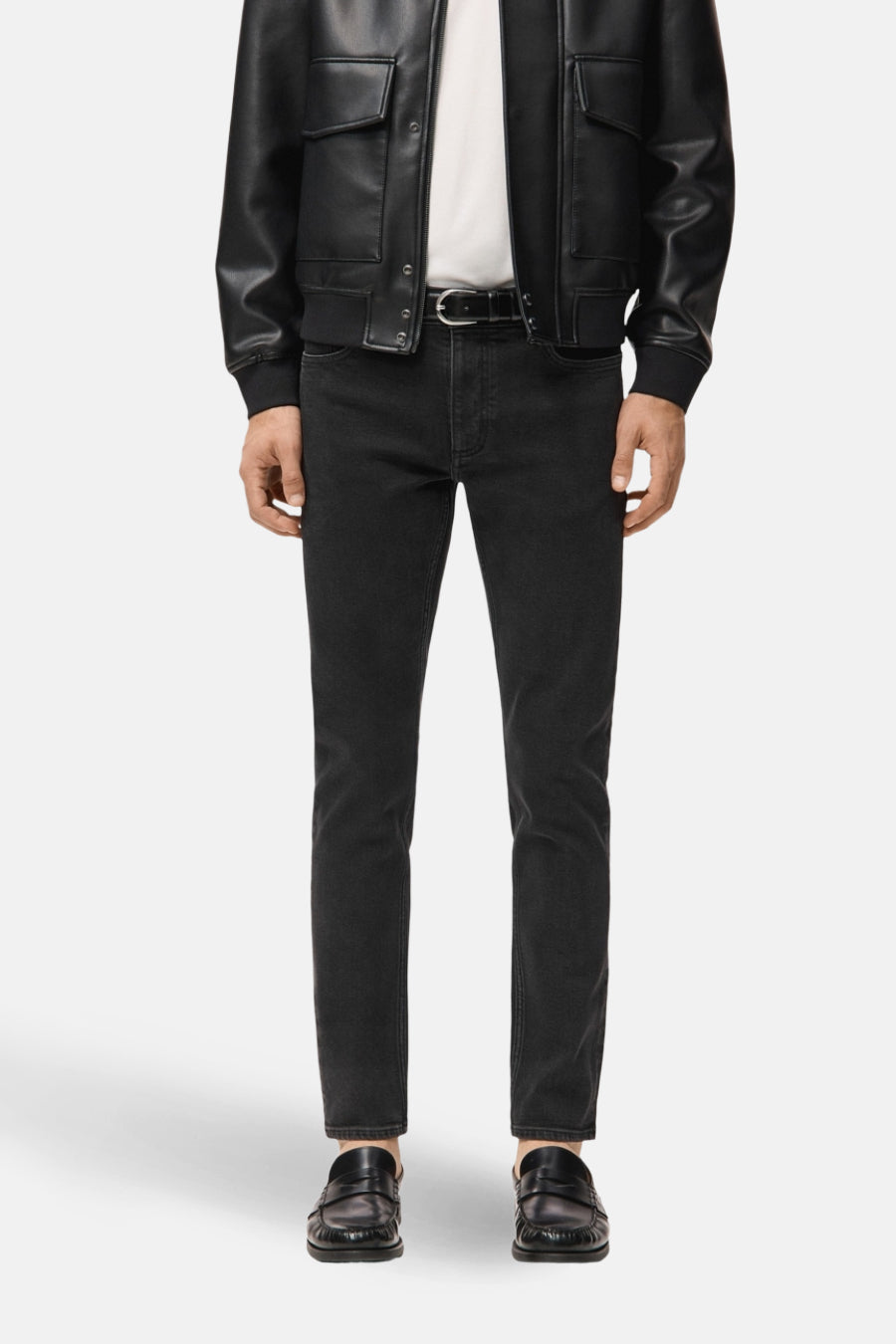 Man in zwarte jeans en leren jas met loafers.
