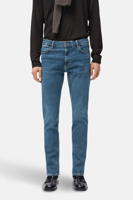 Boutons de jeans foncé en denim bleu foncé de MANGO, vu de l'arrière, avec un t-shirt foncé et des chaussures noires.