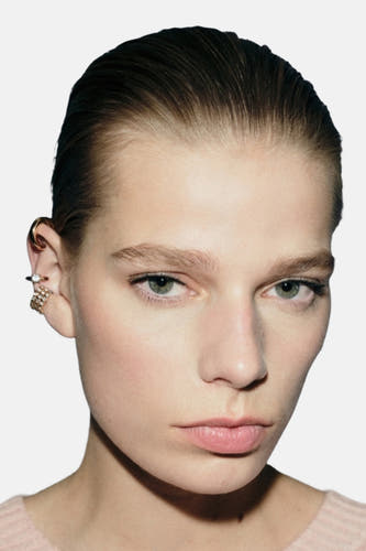 Boucles d'oreilles en or de MANGO, portées avec plusieurs boucles sur l'oreille.