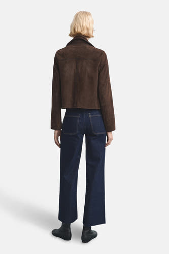 Donkerblauwe wijde jeans van MANGO, met zichtbare zakken en gecombineerd met een bruin jasje.